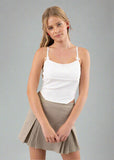 Woman wearing a white top and beige skirt against a plain background