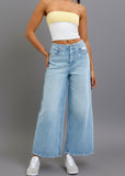 Woman wearing a strapless top and wide-leg jeans on a white background
