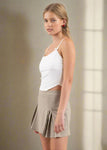 Woman wearing a white top and beige skirt on a plain background