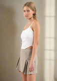 Woman wearing a white top and beige skirt on a plain background