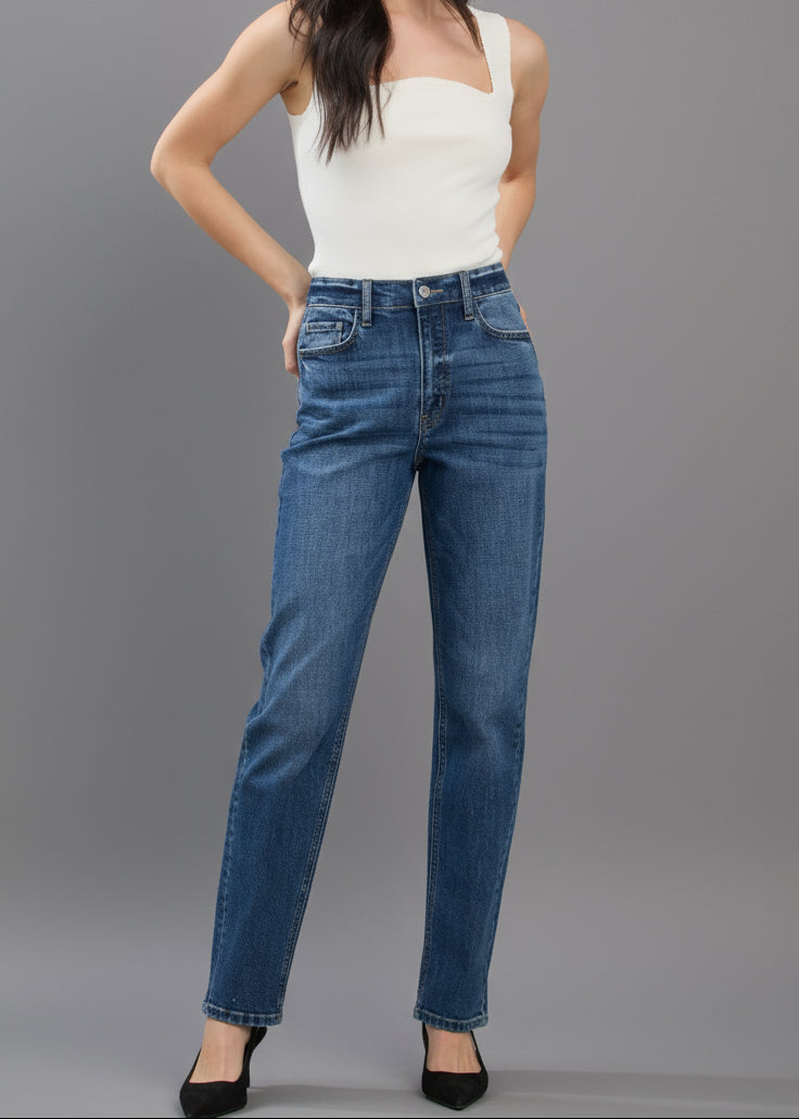 Woman wearing blue jeans and a white top on a plain background