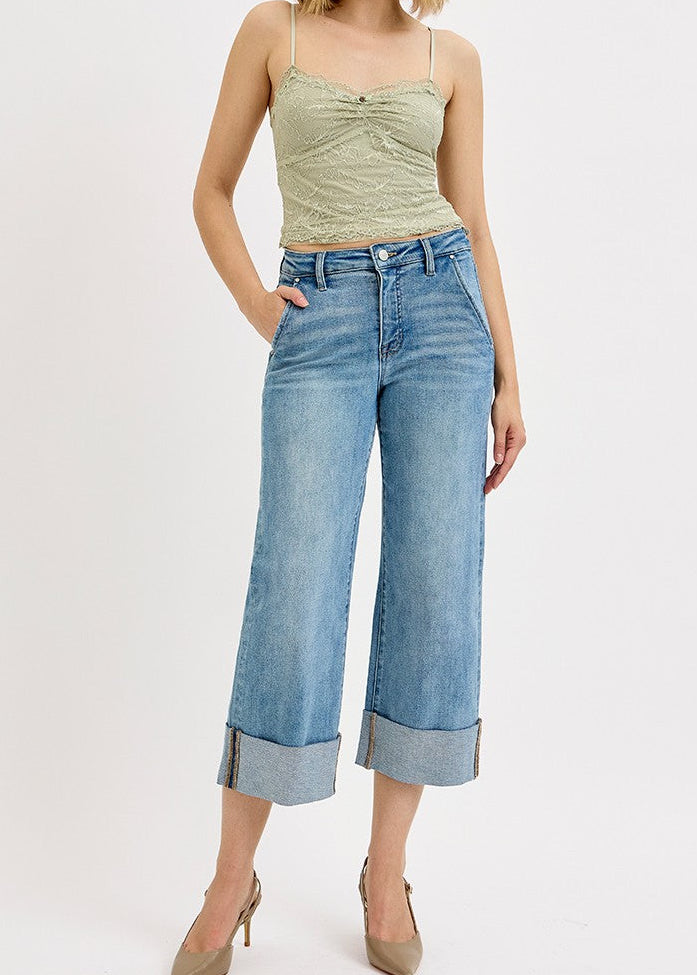 Woman wearing a light green sleeveless top and blue jeans on a white background