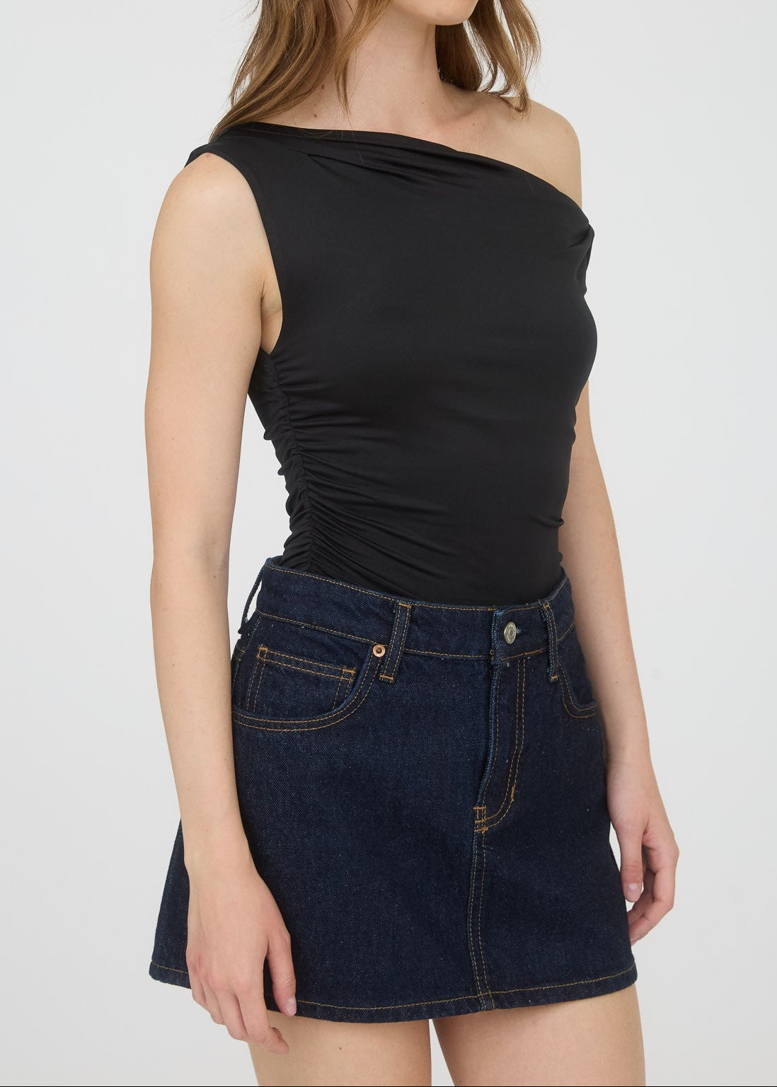 Woman wearing a black top and dark denim skirt on a white background