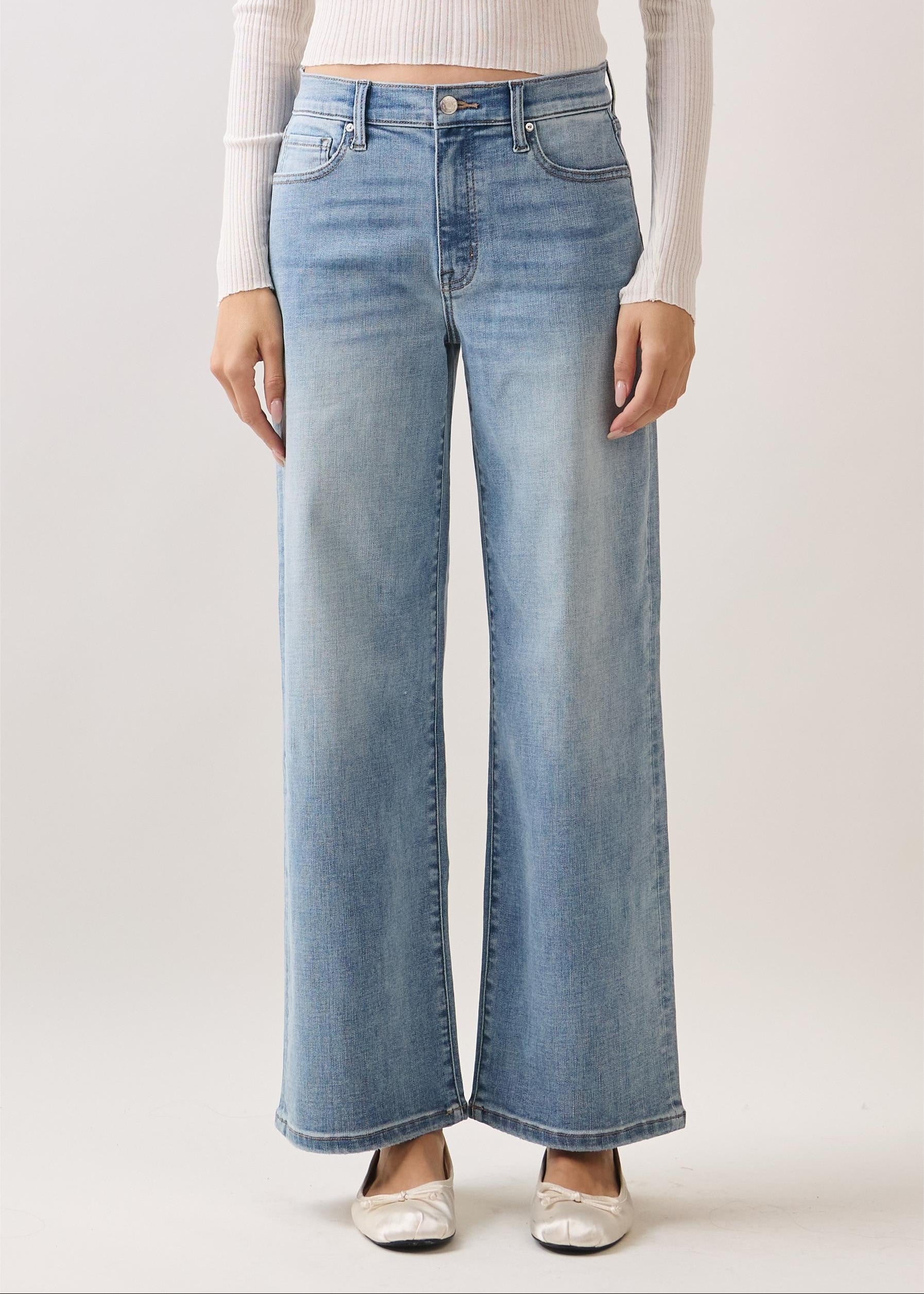 Person wearing light blue jeans on a plain background