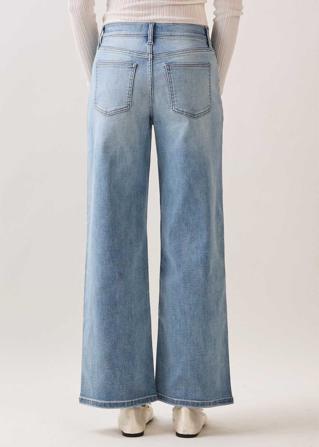 Person wearing light blue wide-leg jeans on a plain background