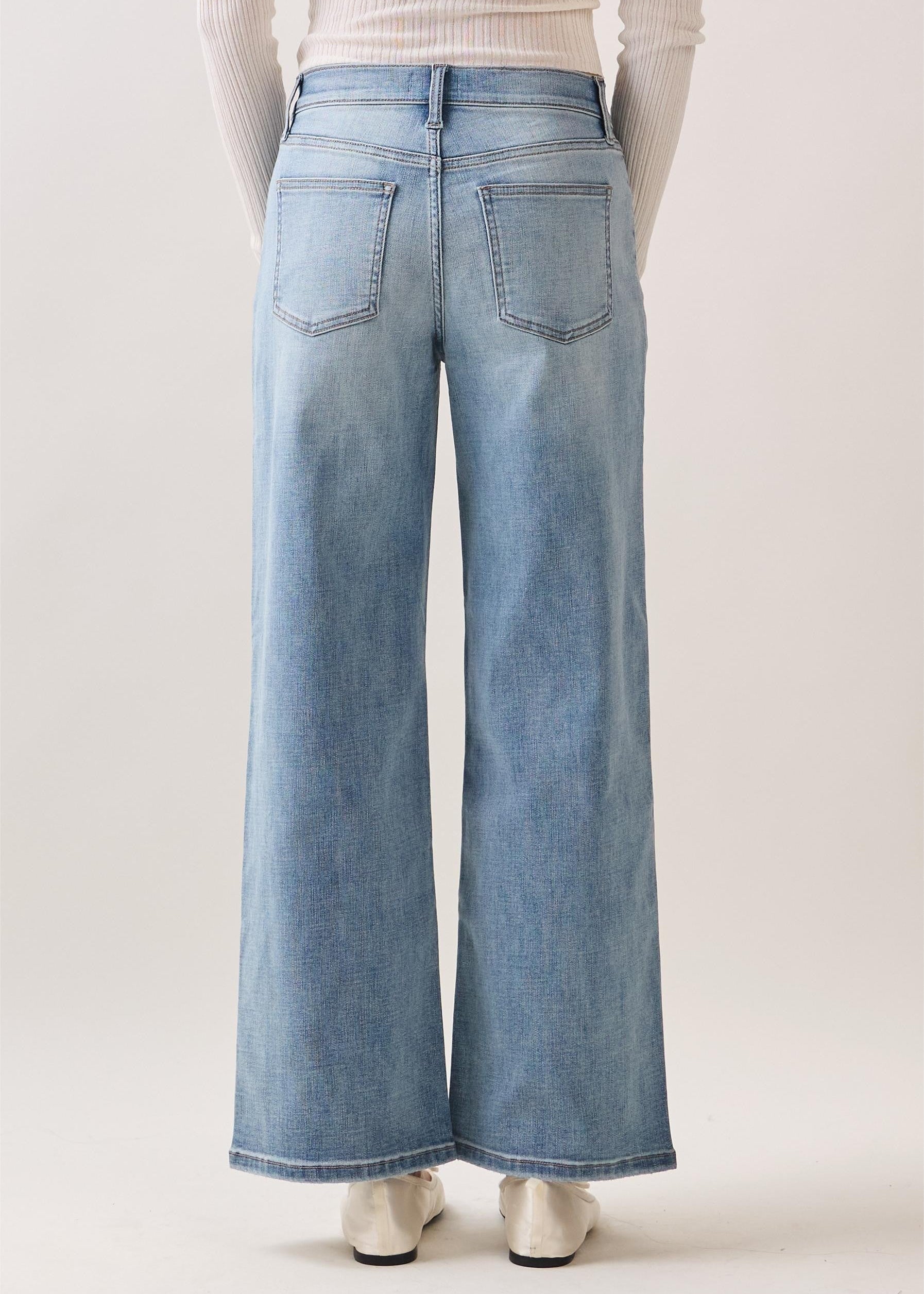 Person wearing light blue wide-leg jeans on a plain background